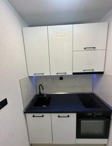 una pequeña cocina con armarios blancos y fregadero en Cloud9, en Split