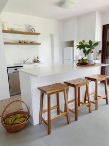 a kitchen with a counter with two stools and a basket of bananas at Birdsong Haven, Lennox Head in Lennox Head