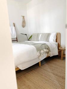 a bedroom with a bed with white blankets and pillows at Birdsong Haven, Lennox Head in Lennox Head