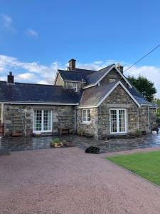 a stone house with a large driveway in front of it at Polharrow in Dalry