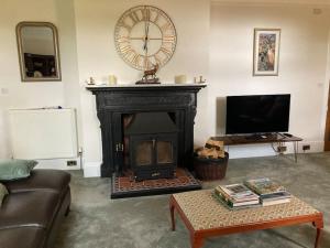 a living room with a fireplace with a clock on the wall at Polharrow in Dalry
