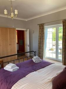 a bedroom with a bed with purple blanket and a window at Polharrow in Dalry