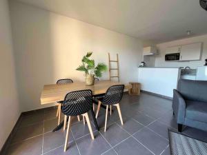 a dining room with a table and chairs and a kitchen at App Le Golf T3 terrasse wifi pkg in Béziers