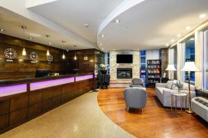 a lobby with a bar with a couch and a tv at Sandman Suites Surrey - Guildford in Surrey