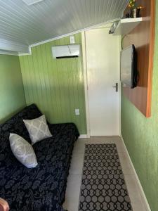 Cette petite chambre comprend un lit, une porte et une télévision. dans l'établissement Recanto das Araucárias - Carazal, Gramado., à Gramado