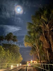 una calle con palmeras por la noche con la luna en Flat no Condomínio Gran Lençóis-Barreirinhas - MA en Barreirinhas