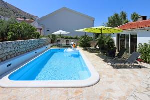 basen z parasolem i krzesłami oraz dom w obiekcie Seaside apartments with a swimming pool Pag - 6412 w mieście Pag