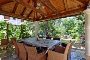 a dining table and chairs under a wooden pergola at Apartments with a parking space Potocnica, Pag - 6338 in Borovići