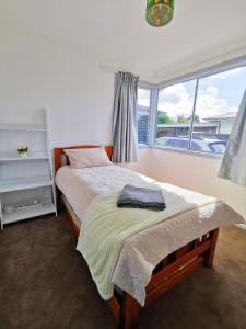 a bedroom with a bed and a large window at 4 bdm house+sleep-out in Pukete.Close to The Base in Hamilton