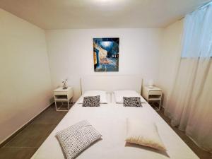 ein weißes Zimmer mit einem Bett mit zwei Kissen in der Unterkunft Apartments Ivanka in Supetar