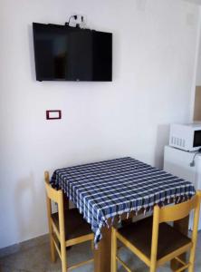 een tafel met twee stoelen en een tv aan de muur bij Petkovic Guesthouse in Žabljak