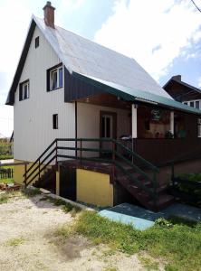 a white house with a gambrel roof and a porch at Petkovic Guesthouse in Žabljak