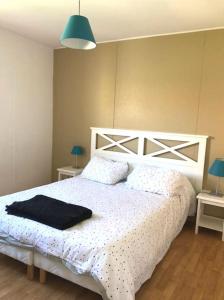 a bedroom with a white bed with a black blanket on it at Charmante petite maison in Soustons +13 photos