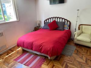 1 dormitorio con 1 cama grande de color rojo con silla en Imperdible Monoambiente en Palermo Chico 10min Aeroparque 100m Mater Dei en Buenos Aires
