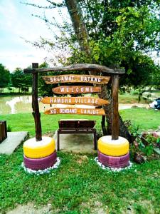 a wooden sign in a park with a bench at Family Room HAMSHA VILLAGE 