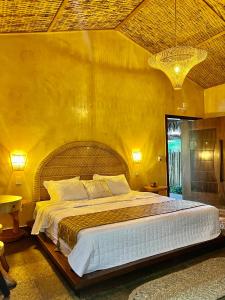 a bedroom with a large bed in a yellow wall at Pousada Rancho das Dunas in Santo Amaro