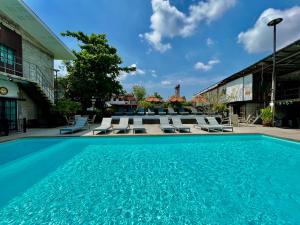 a swimming pool with blue water and lounge chairs at The Warehouse Chiang Mai in Chiang Mai