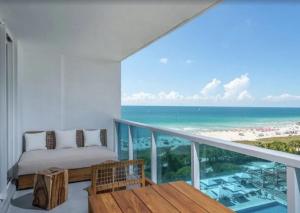 - un balcon avec un lit et une vue sur la plage dans l'établissement 1 Hotel & Homes Miami Beach Oceanfront Residence Suites By Joe Semary, à Miami Beach