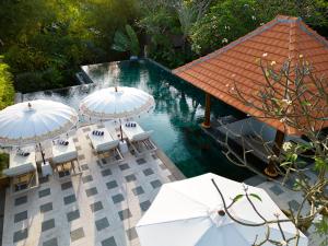una piscina con ombrelloni e sedie bianchi accanto all'acqua di Adepa Resort a Canggu