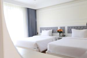 two beds in a white room with a window at Nature Hotel - Pham Hong Thai in Da Lat