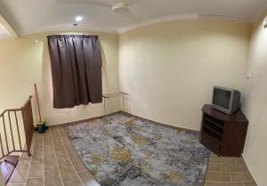 Zimmer mit einem TV auf einer Kommode und einem Fenster in der Unterkunft Naufa Homestay 2 3R3B Machang in Macang
