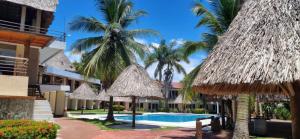 un complejo con piscina y palmeras en Hotel MarBrissa, en Puerto Barrios