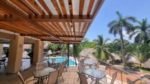 a patio with tables and chairs and a swimming pool at Hotel MarBrissa in Puerto Barrios
