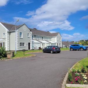 two cars parked in a parking lot in front of a house at Fairway Haven in Dunfanaghy