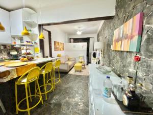eine Küche und ein Wohnzimmer mit gelben Stühlen und einem Tisch in der Unterkunft Hostel quartos privativos rio vermelho in Salvador
