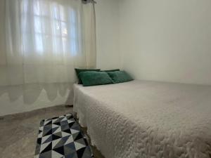 1 cama con almohadas verdes en una habitación con ventana en Sitio Boa Esperança 20km de Monte Verde en Camanducaia
