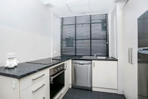 a kitchen with white cabinets and a black counter top at CLD01 - 1 bedroom unit - Bridge Street, Sydney CBD in Sydney