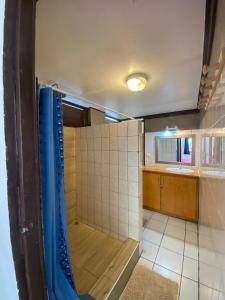 a bathroom with a shower with a tiled floor and a sink at MOOREA - Fare Tiki Beach in Haapiti
