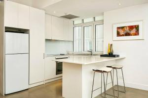 a kitchen with white cabinets and a counter with stools at CLDON- furnished 1 bedroom - Bridge St Sydney CBD in Sydney