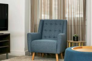 a blue chair in a living room with a tv at CLDON- furnished 1 bedroom - Bridge St Sydney CBD in Sydney