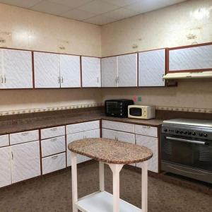 a kitchen with white cabinets and a table in it at Alnessayem Farmhouse in Sayḩ aş Şaqlah