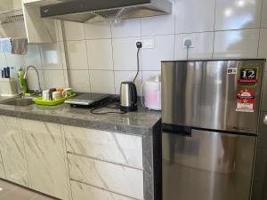 a kitchen with a stainless steel refrigerator and a sink at Sandakan Homestay Coastal Serenity 山海绿栖 in Sandakan