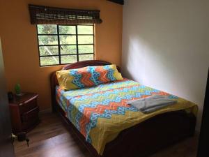 Un dormitorio con una cama con un edredón colorido y una ventana en Finca el Mirador oasis de paz en Sasaima