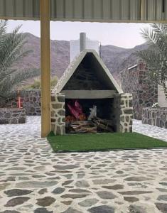 a stone fireplace with a dog inside of it at Alsalam Farmhouse in Hatta