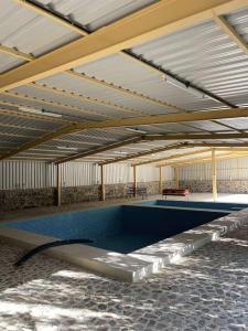 a swimming pool in a building with a roof at Alsalam Farmhouse in Hatta