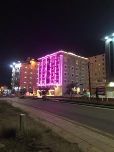 un edificio iluminado con luces rosas en una calle en فندق وشقق ليالي الاحلام للشقق المخدومه en Baljursi