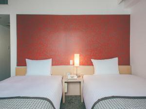 duas camas num quarto com uma parede vermelha em Hamilton Hotel Red em Nagoia
