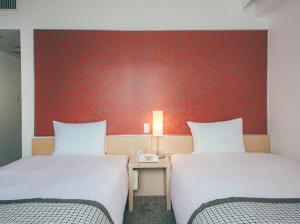 two beds in a room with a red wall at Hamilton Hotel Red in Nagoya