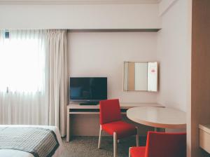 um quarto de hotel com uma cama e uma secretária com uma televisão em Hamilton Hotel Red em Nagoia