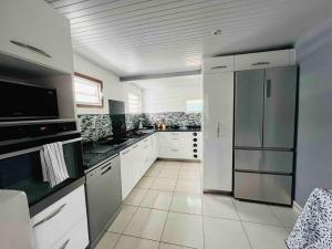 a large kitchen with white cabinets and a stainless steel refrigerator at Charmante Villa, kaz’ AA.Liyah in Pointe-à-Pitre