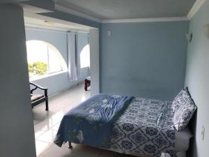 a blue bedroom with a bed and a window at Pousada Recanto Marinho in Arraial do Cabo