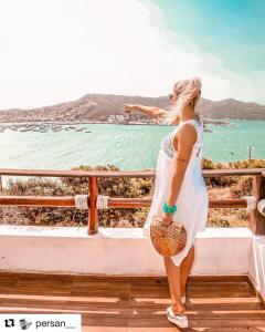 a woman standing on a balcony looking at the ocean at Pousada Recanto Marinho in Arraial do Cabo