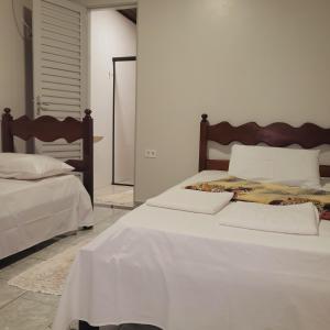 a bedroom with two beds with white sheets and a mirror at Hilton Hotel in Barra do Garças