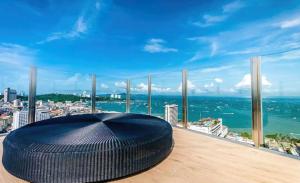 a large black ottoman on a balcony with a view of the ocean at BASE Central PATTAYA Quiet King-Bed with Infinity Pool & Free Netflix in Pattaya Central
