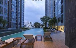 una piscina con sillas, mesas y edificios en BASE Central PATTAYA Quiet Room with Infinity Pool & Free Netflix en Pattaya centro