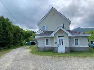 a house on a gravel road next to a driveway at Furano Rental House in Furano